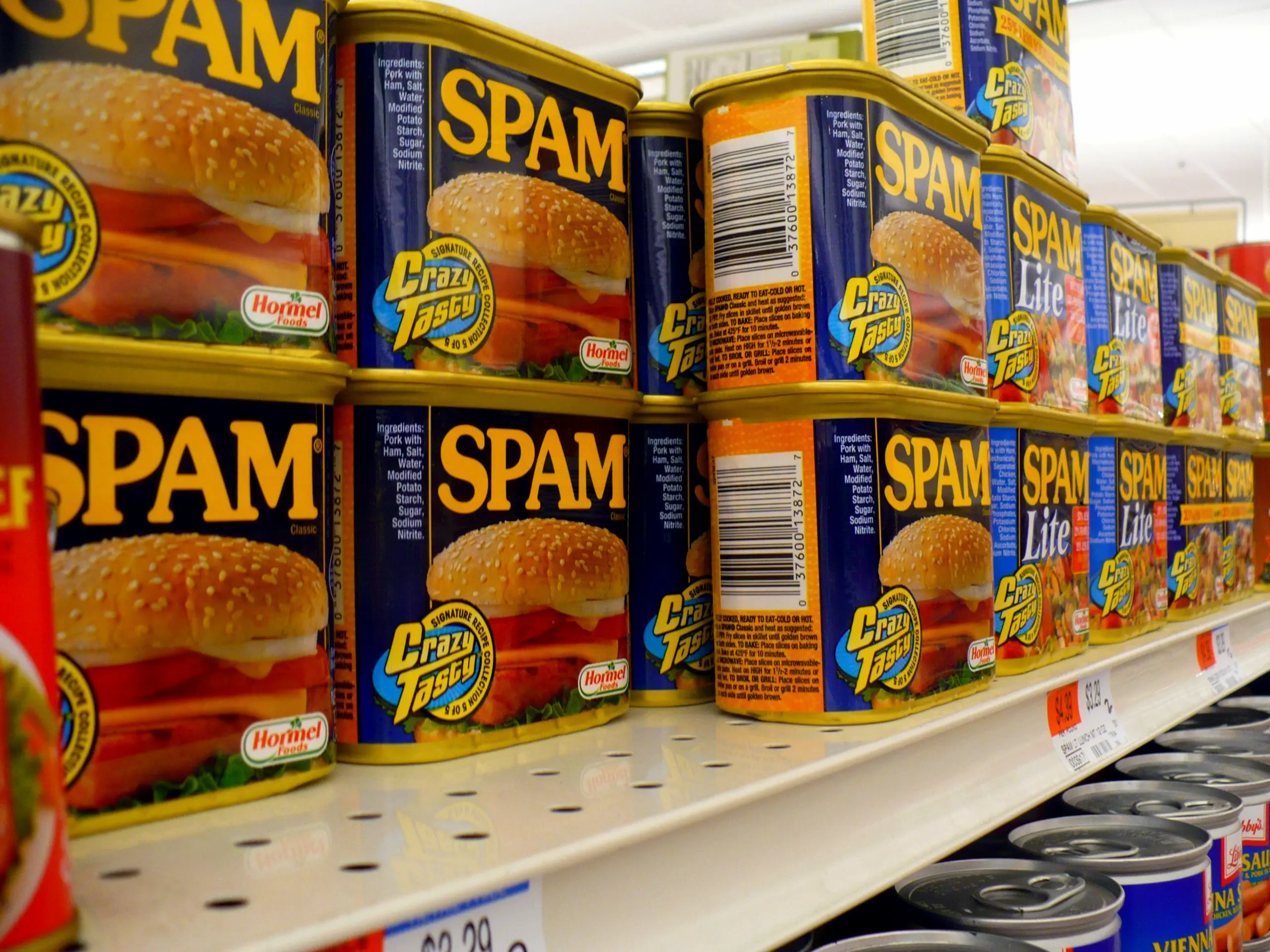 a front facing photo of a grocery store shelf lined with cans of spam stacked in twos